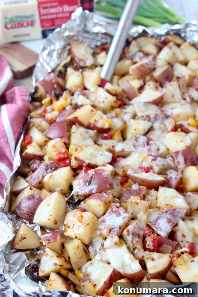 cheesy grilled cubed potatoes in foil with spatula