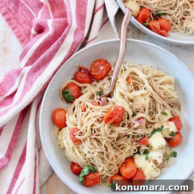 cooked angel hair pasta in bowl with cherry tomatoes, basil and mozzarella cheese
