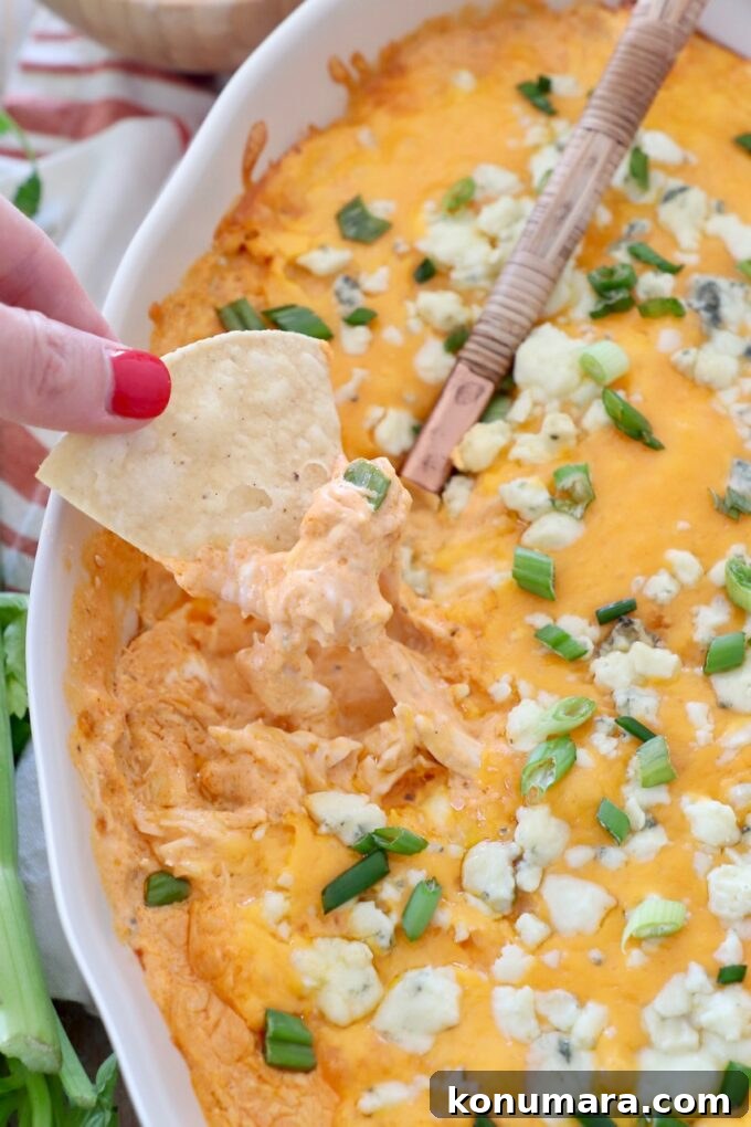 Instant Pot Shredded Chicken Recipe: Juicy and Tender 9 hand lifting chip out of buffalo chicken dip in baking dish