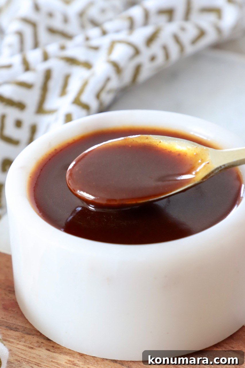 stir fry sauce in small white bowl with gold spoon dipped into the sauce