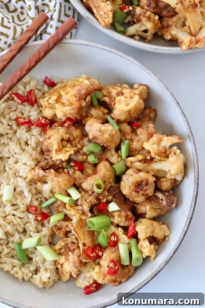 fried cauliflower tossed in general tso sauce in bowl with brown rice