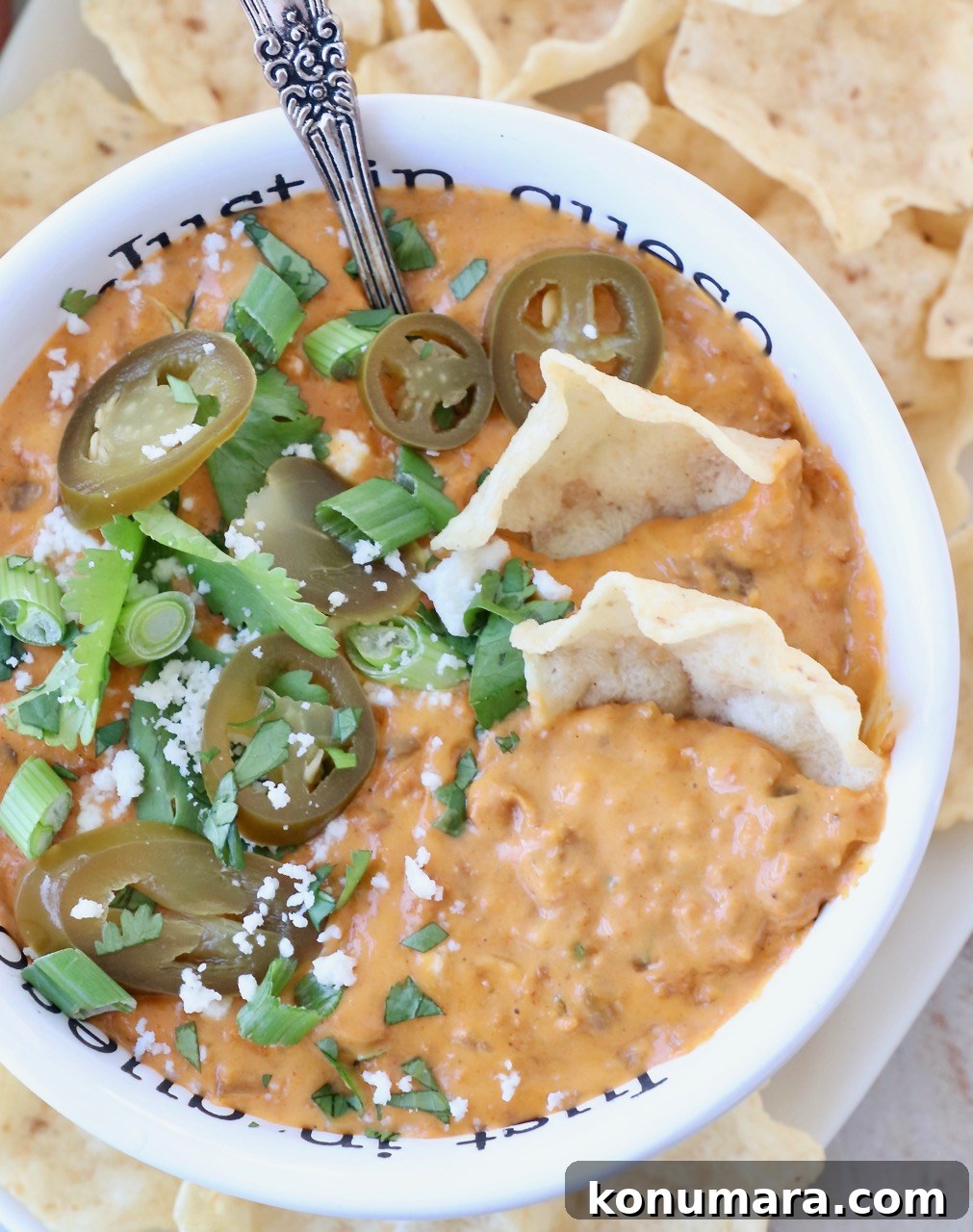 chorizo queso dip in bowl with tortilla chips and sliced jalapenos