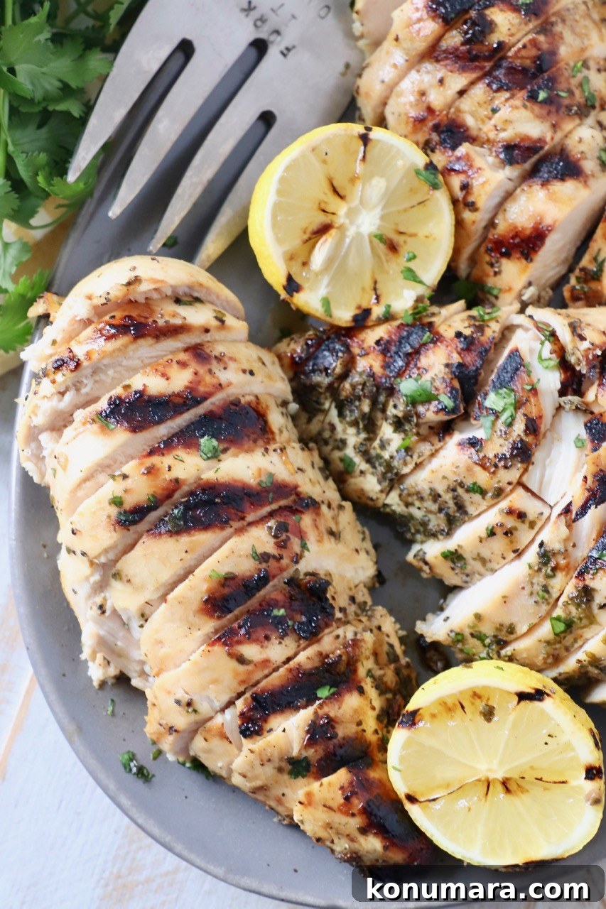 sliced grilled chicken on platter with fork and lemon slices
