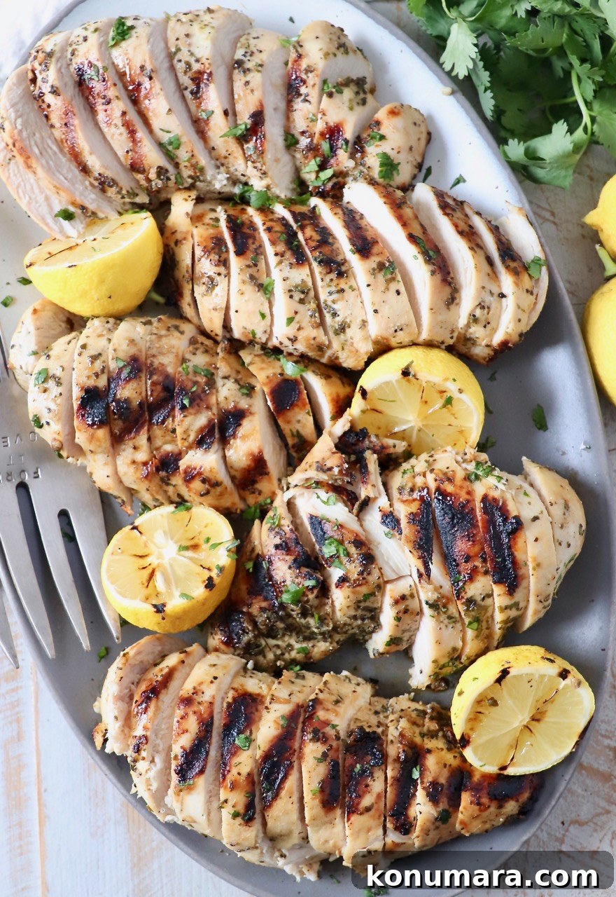 sliced grilled chicken breasts on plate with lemons