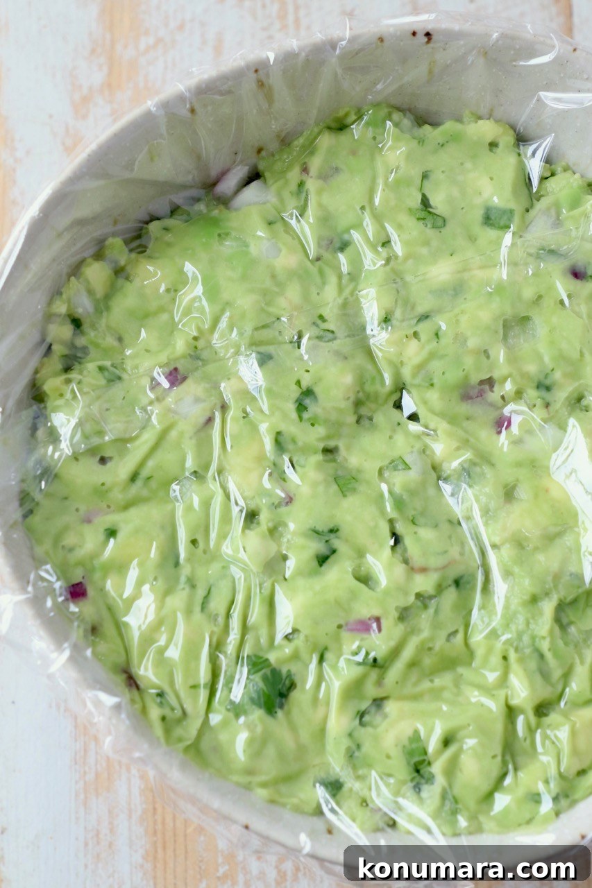 guacamole in bowl with plastic wrapped pressed on top