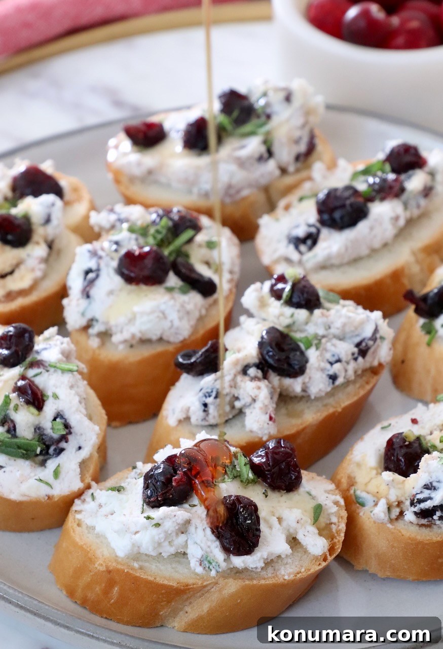Honey drizzling over cranberry goat cheese crostini on a plate