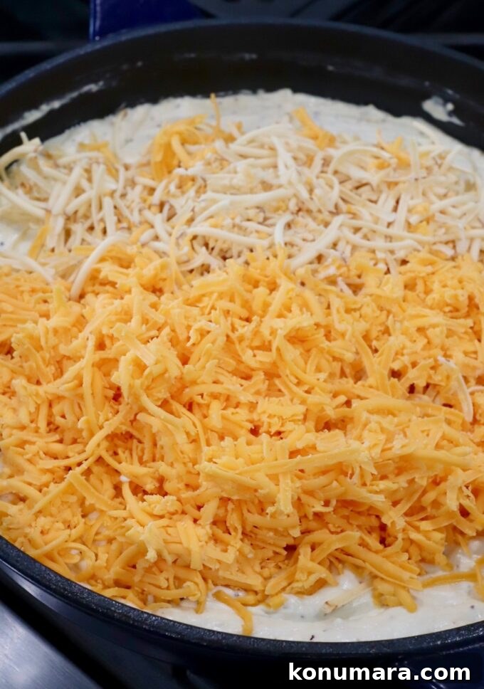 shredded cheese in skillet of creamy sauce