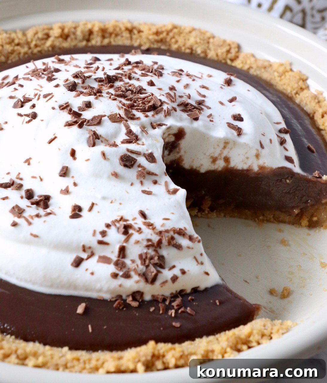 chocolate pie with whipped cream topping in pie plate with slice taken out of the pie