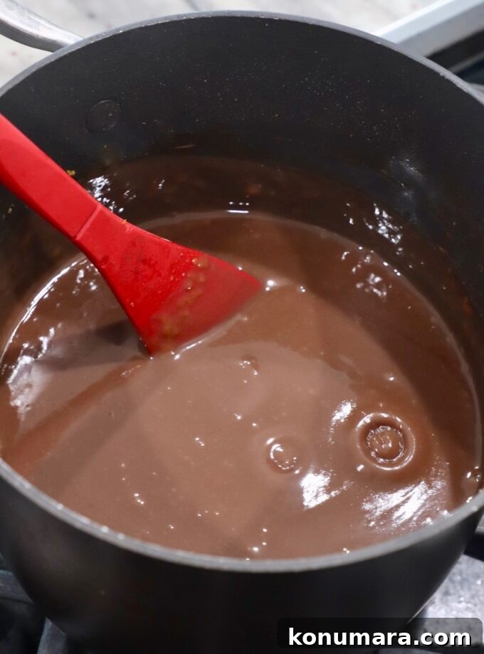 red spoon stirring chocolate pie filling in saucepan