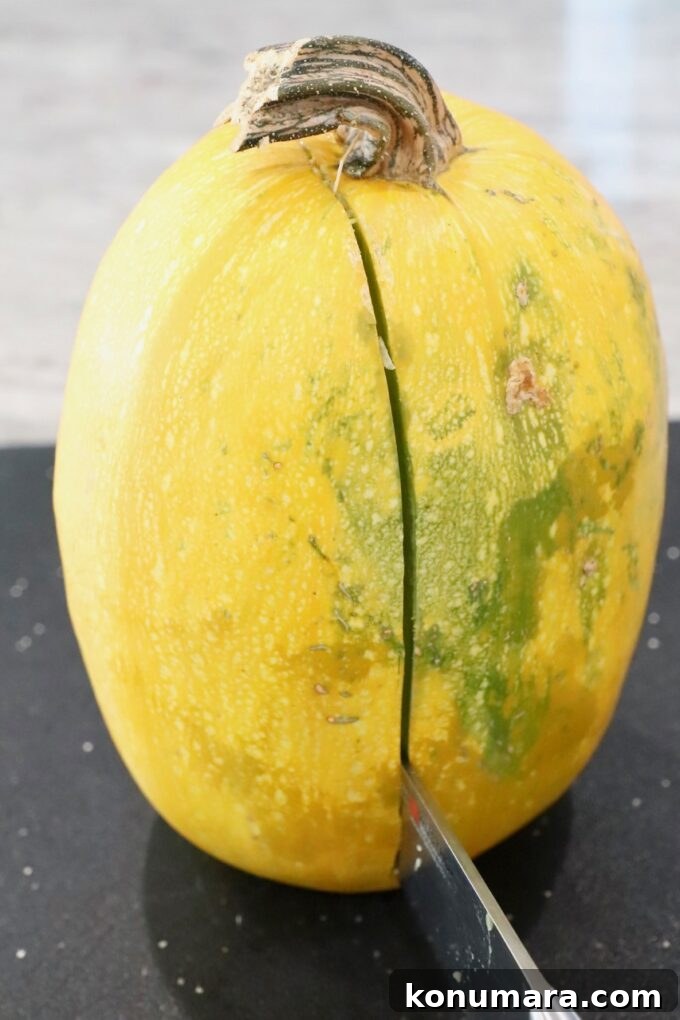 spaghetti squash on cutting board with knife slicing through the middle