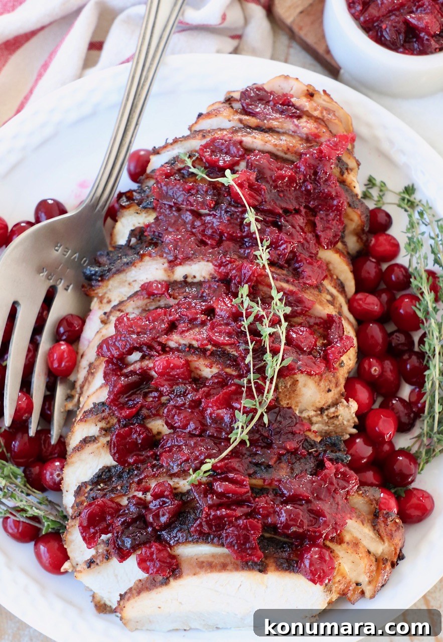 sliced turkey breast covered in cranberry sauce on plate with large serving fork