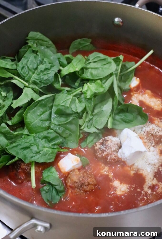 Classic Homemade Meatball Soup Recipe 7 spinach and cheese in pot of soup