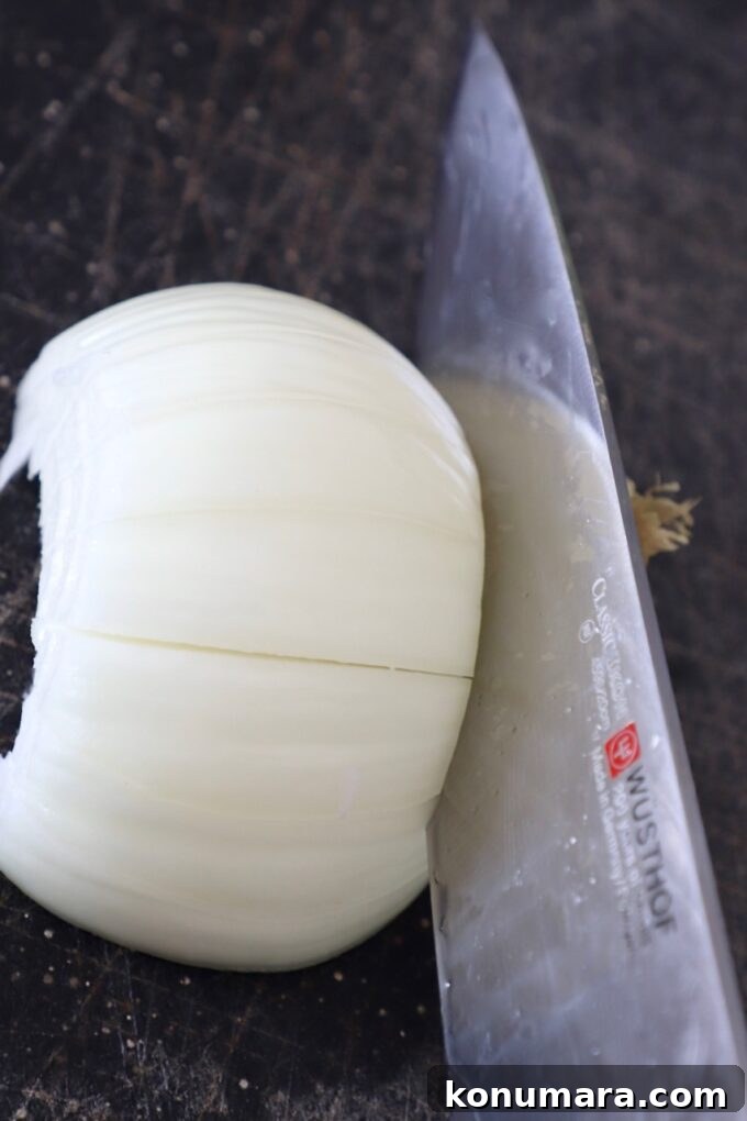 Caramelizing Onions: Step-by-Step Guide 5 knife cutting an onion on cutting board