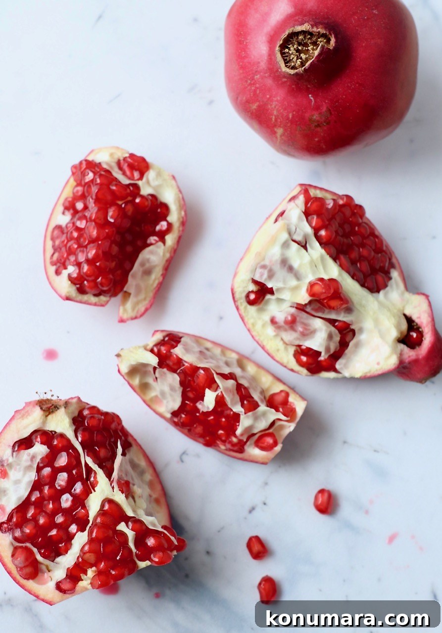 pomegranate cut into pieces on white cutting board