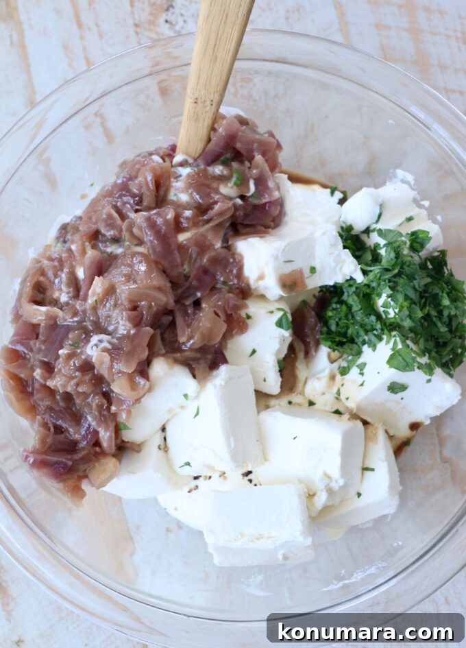 ingredients for caramelized onion dip in glass bowl with spatula