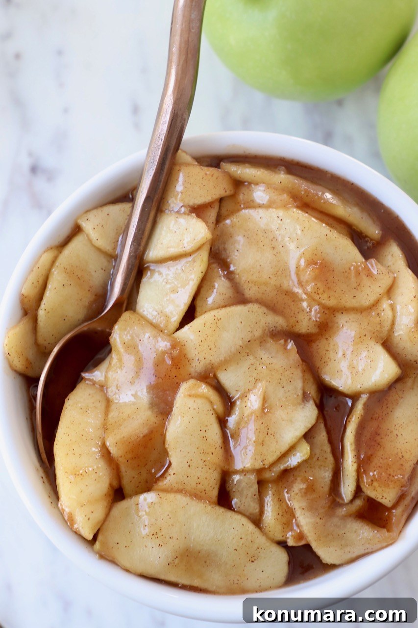 prepared apple pie filling in white bowl with copper spoon