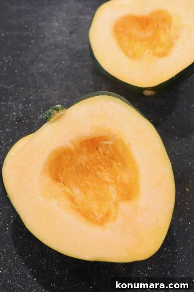 acorn squash cut in half on cutting board with the seeds removed