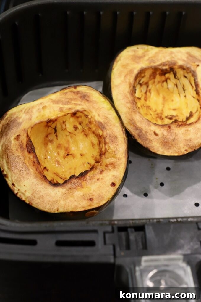 cooked acorn squash cut in half in air fryer basket