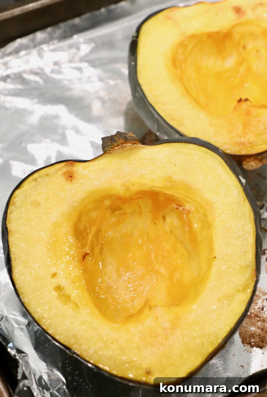 roasted acorn squash cut in half on foil-lined baking sheet