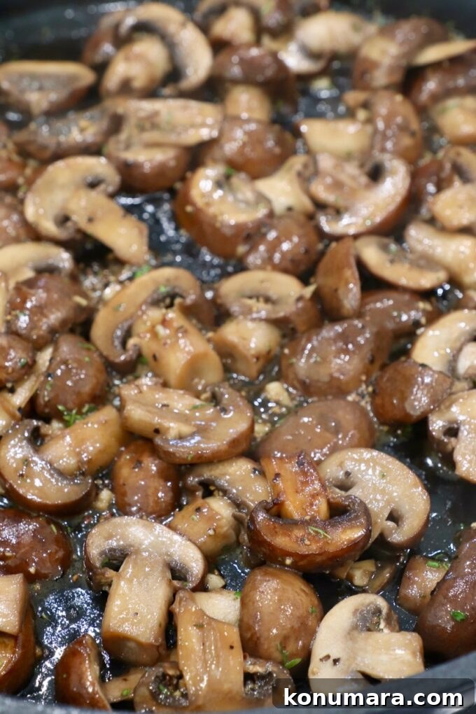 Garlic Butter Sauteed Mushrooms with Herbs 7 cooked sliced mushrooms in skillet