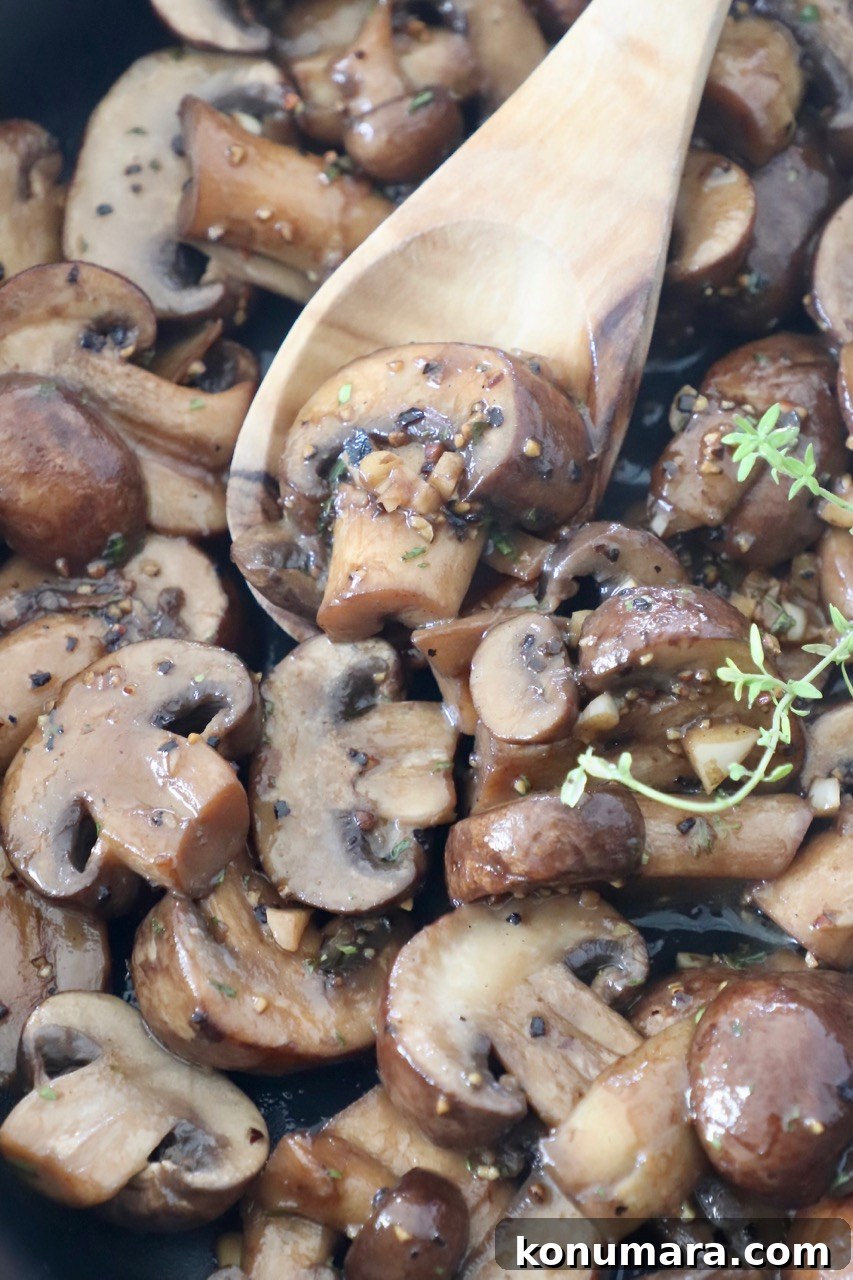 Garlic Butter Sauteed Mushrooms with Herbs 9 sauteed mushrooms in skillet with wooden spoon