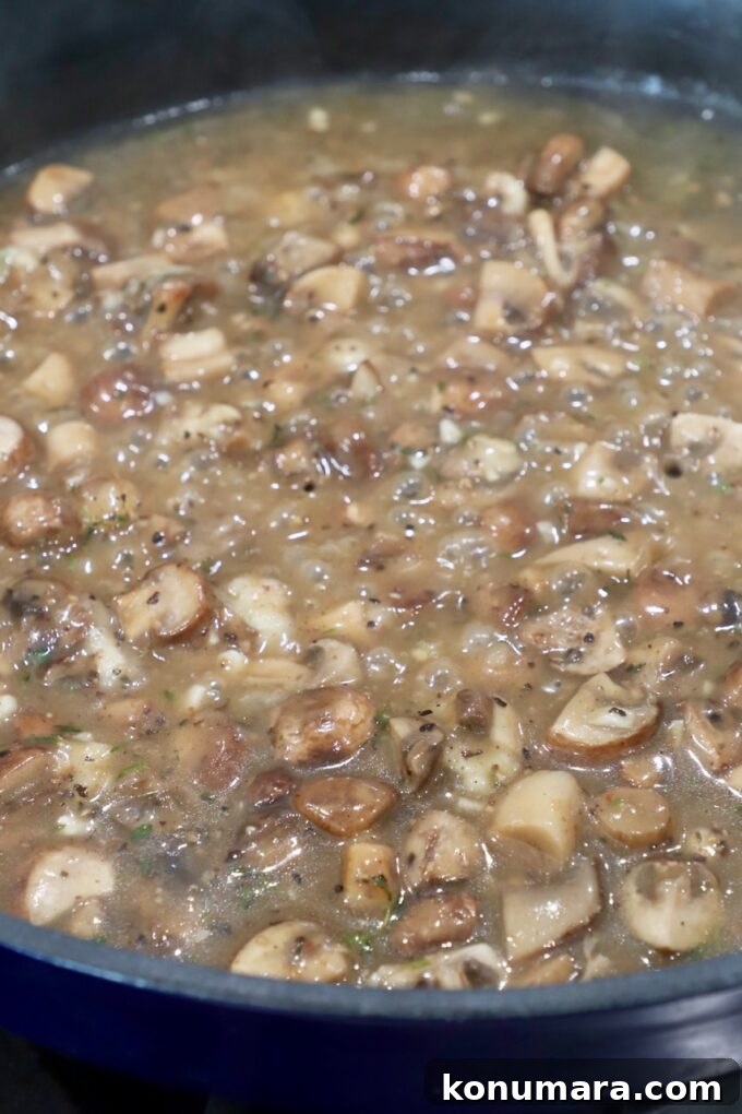Velvety Cream of Mushroom Soup Recipe 6 diced mushrooms simmering in broth in skillet