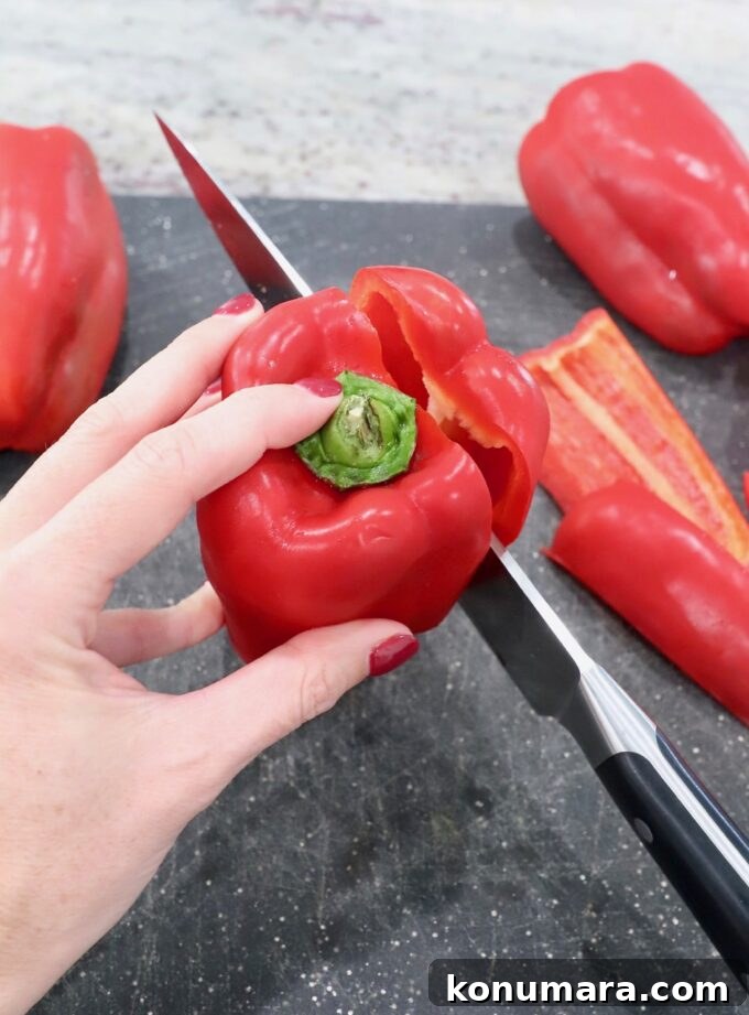 knife slicing into red bell pepper on cutting board