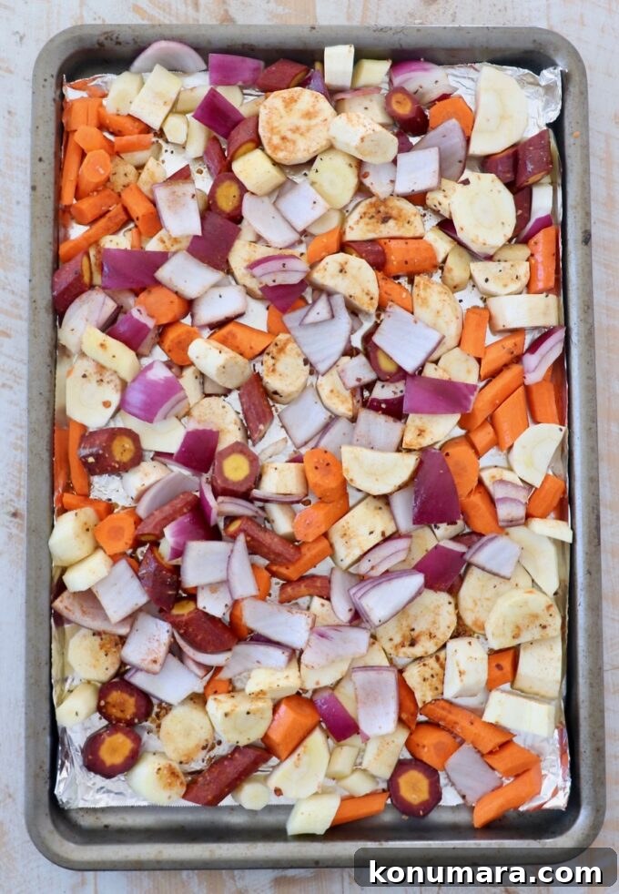 Oven-Roasted Root Vegetables with Garlic and Herbs 4 Uncooked diced vegetables on a parchment-lined baking sheet
