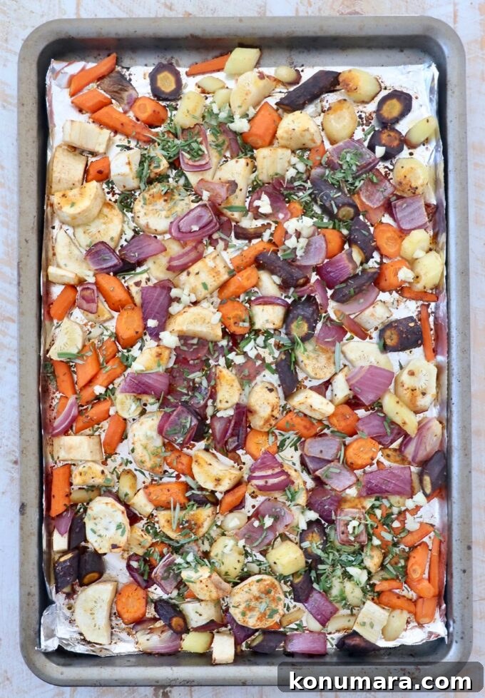Oven-Roasted Root Vegetables with Garlic and Herbs 5 Diced vegetables on a baking sheet with fresh chopped rosemary