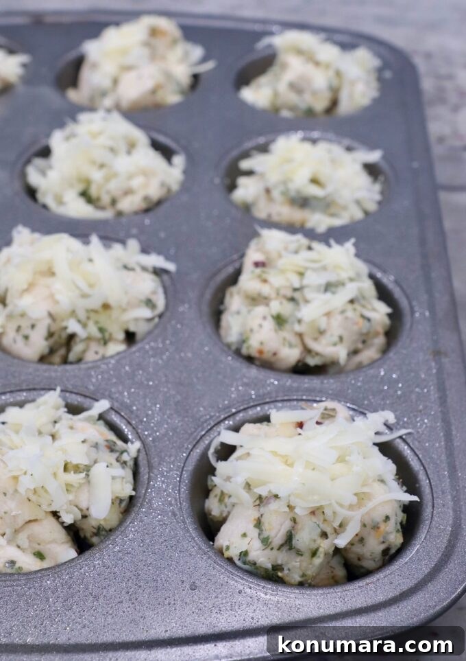 uncooked dough in muffin tin topped with shredded cheddar cheese