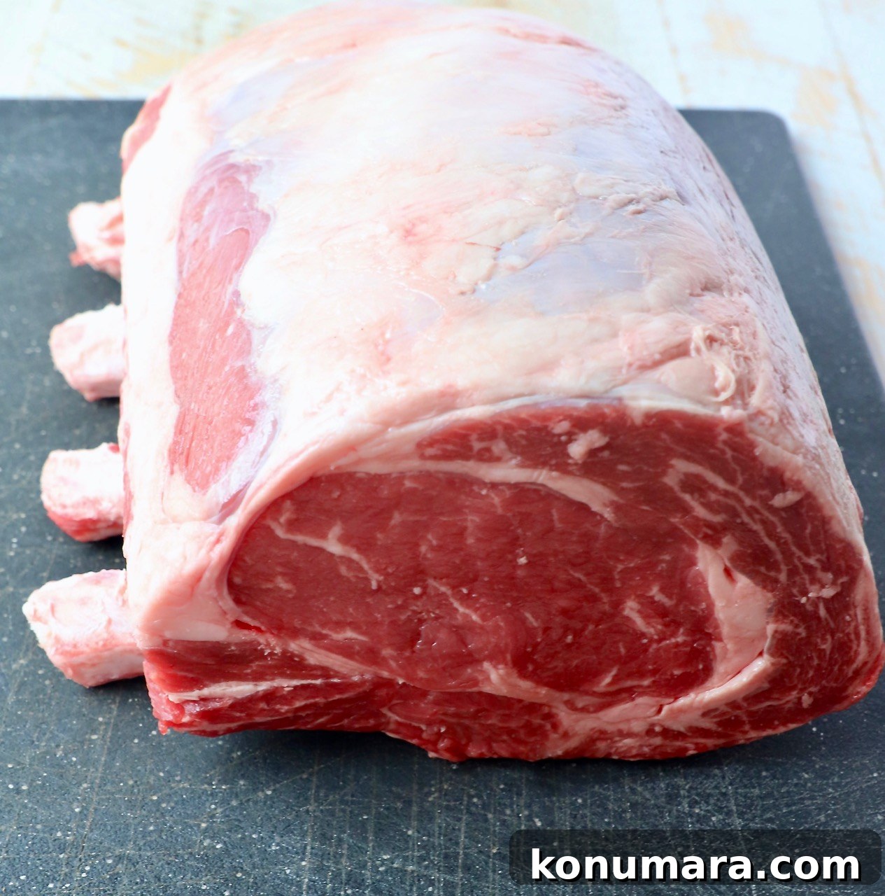 Oven-Roasted Bone-In Prime Rib with Garlic and Rosemary 3 uncooked bone in prime rib on cutting board