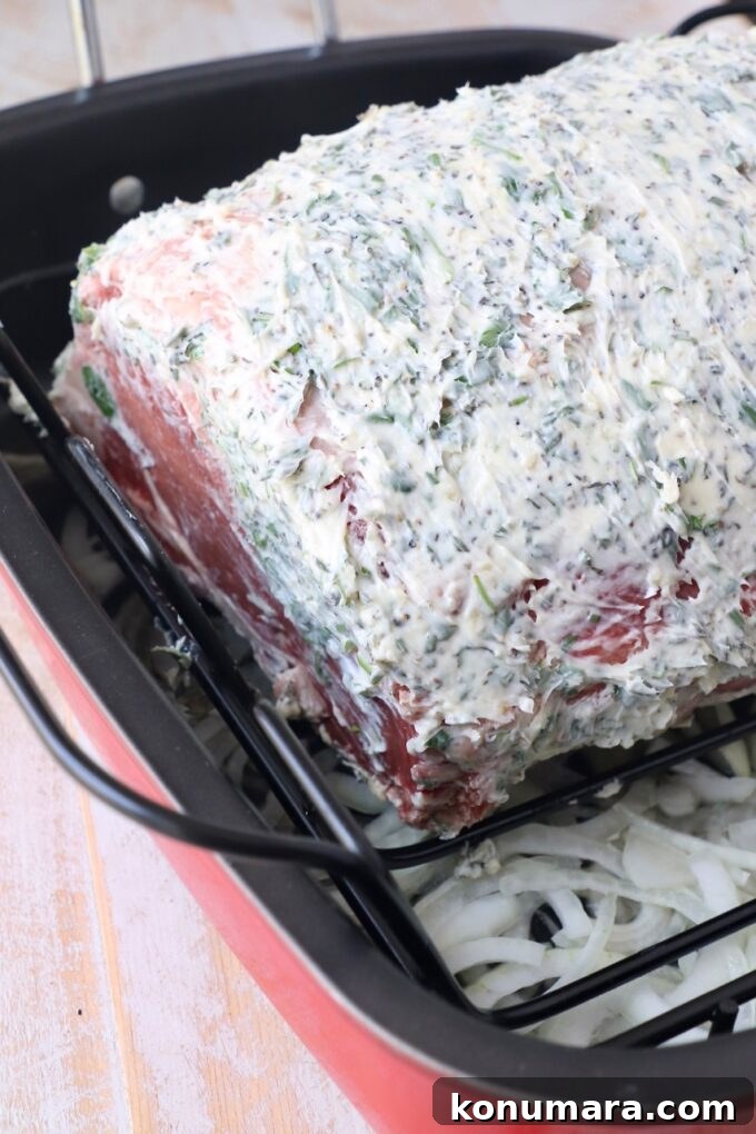 Oven-Roasted Bone-In Prime Rib with Garlic and Rosemary 5 herb butter rubbed ribeye roast in roasting pan with sliced onions