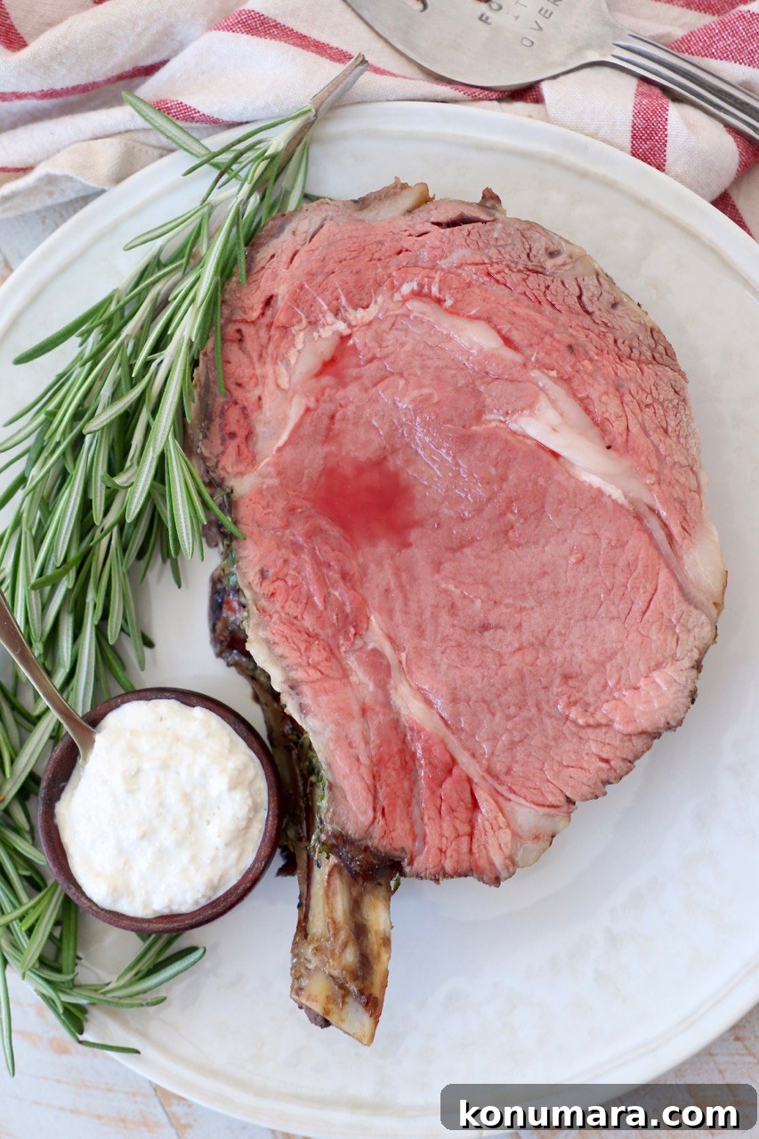 Oven-Roasted Bone-In Prime Rib with Garlic and Rosemary 10 slice of cooked prime rib on plate with horseradish sauce in bowl