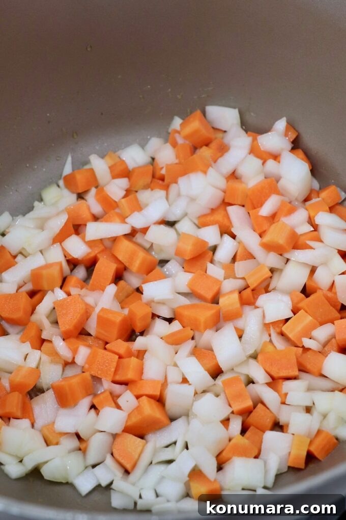 Creamy Roasted Acorn Squash Soup Recipe 5 diced carrots and onions in pot on the stove