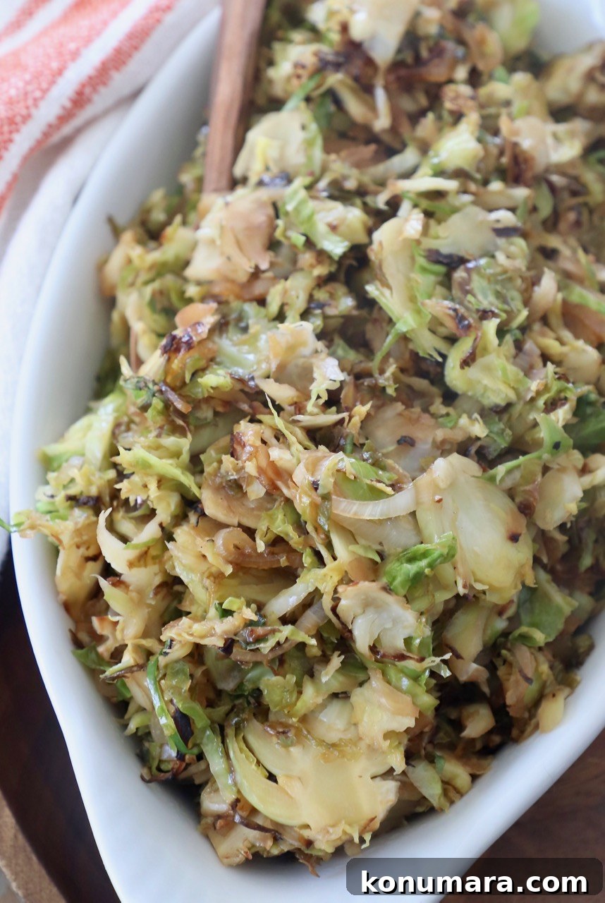 Shredded Brussels Sprouts Slaw with Lemon Vinaigrette 2 sauteed shredded brussels sprouts in white serving dish with fork