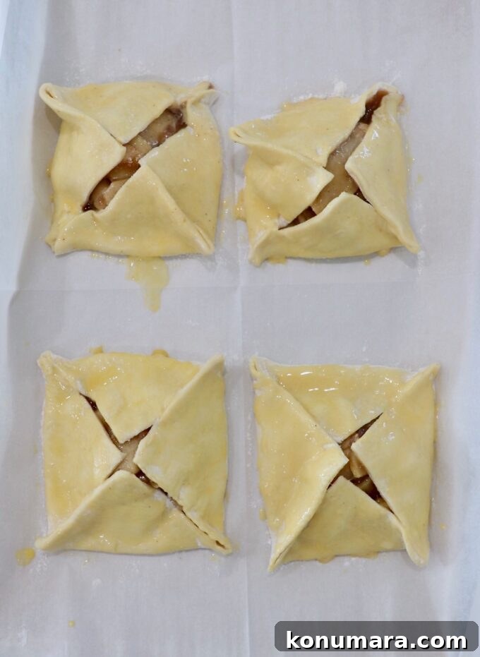 Classic Flaky Apple Danish with Cinnamon Filling 8 four uncooked apple danish brushed with egg wash on parchment paper