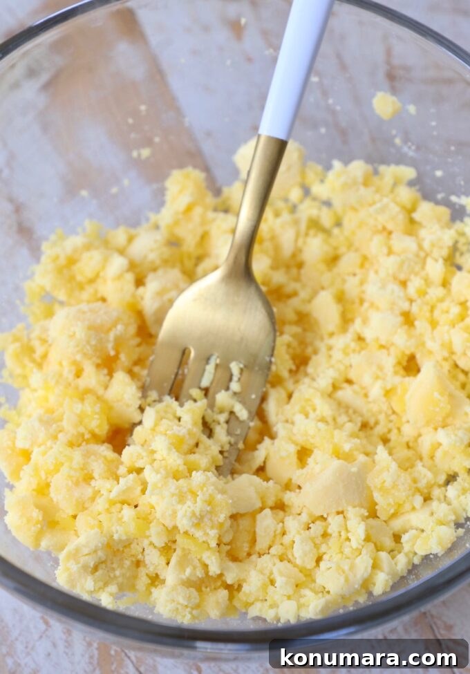 smashed egg yolks in glass bowl with fork