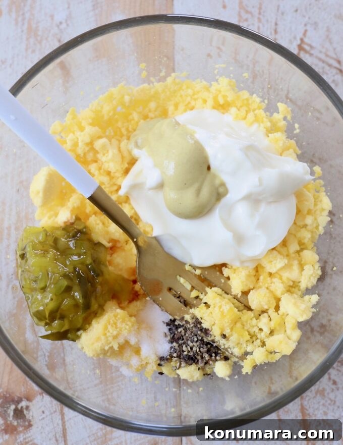 deviled egg filling ingredients in glass bowl with fork