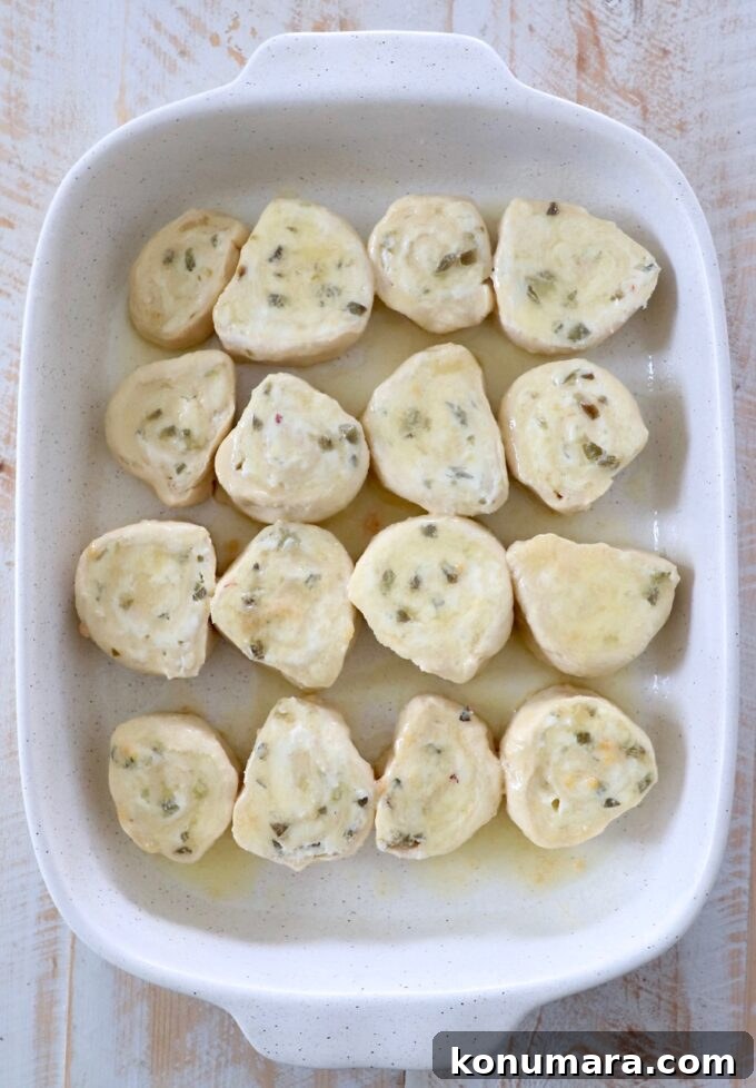 Cheesy Jalapeno Popper Crescent Rolls 12 garlic butter spread on top of uncooked jalapeno popper crescent rolls in casserole dish