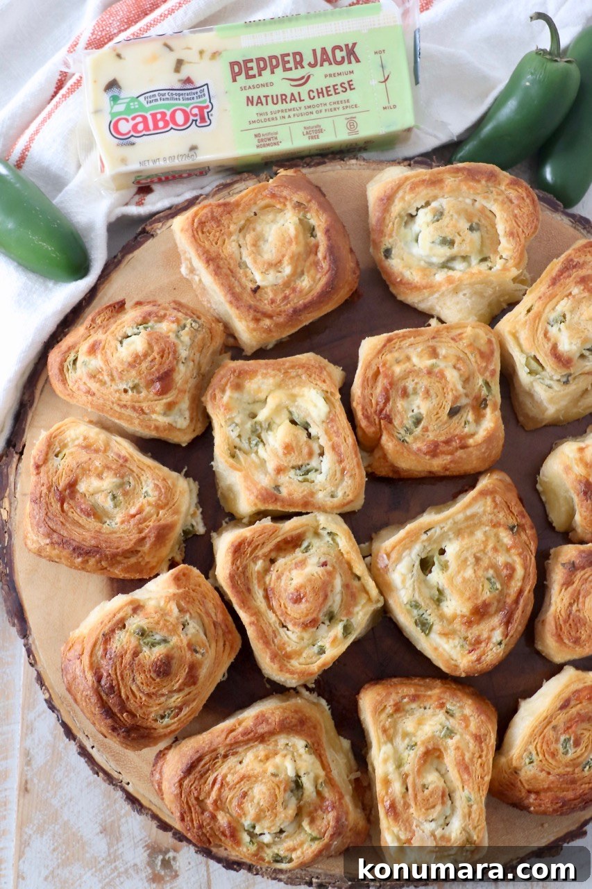 Cheesy Jalapeno Popper Crescent Rolls 14 jalapeno popper crescent rolls on wood serving board with jalapenos and a block of cheese on the side