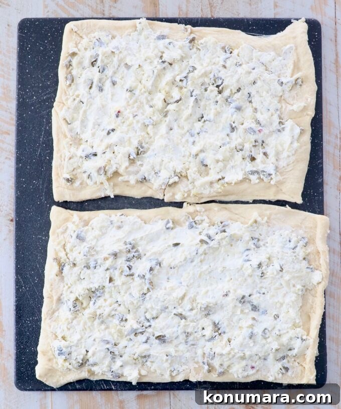 Cheesy Jalapeno Popper Crescent Rolls 7 crescent roll dough covered in jalapeno cheese mixture on cutting board