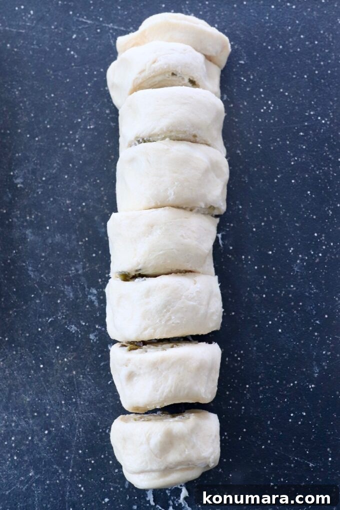 Cheesy Jalapeno Popper Crescent Rolls 10 crescent roll dough rolled up and sliced on cutting board