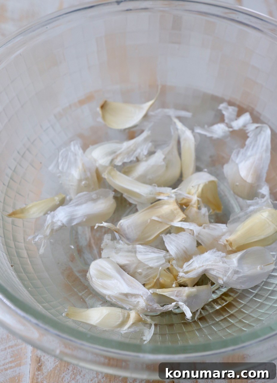 unpeeled garlic cloves in glass bowl of water