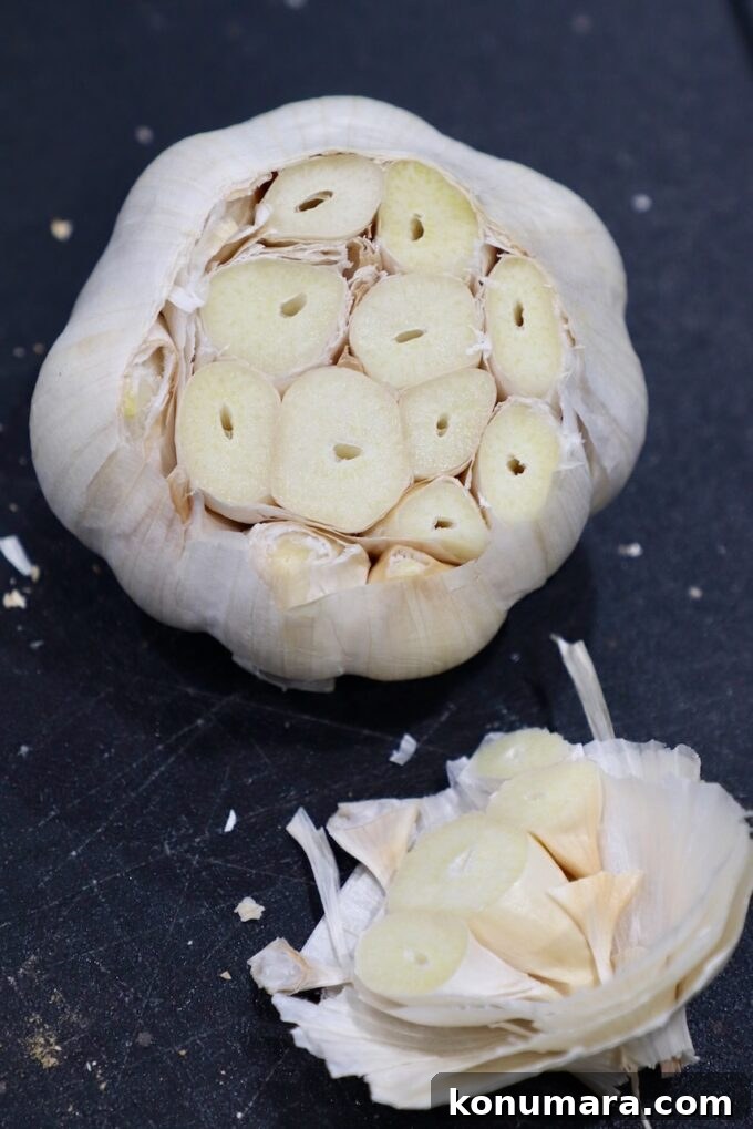 head of garlic with the top cut off on cutting board