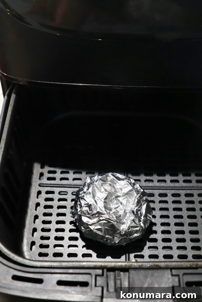 head of garlic wrapped in foil in air fryer basket