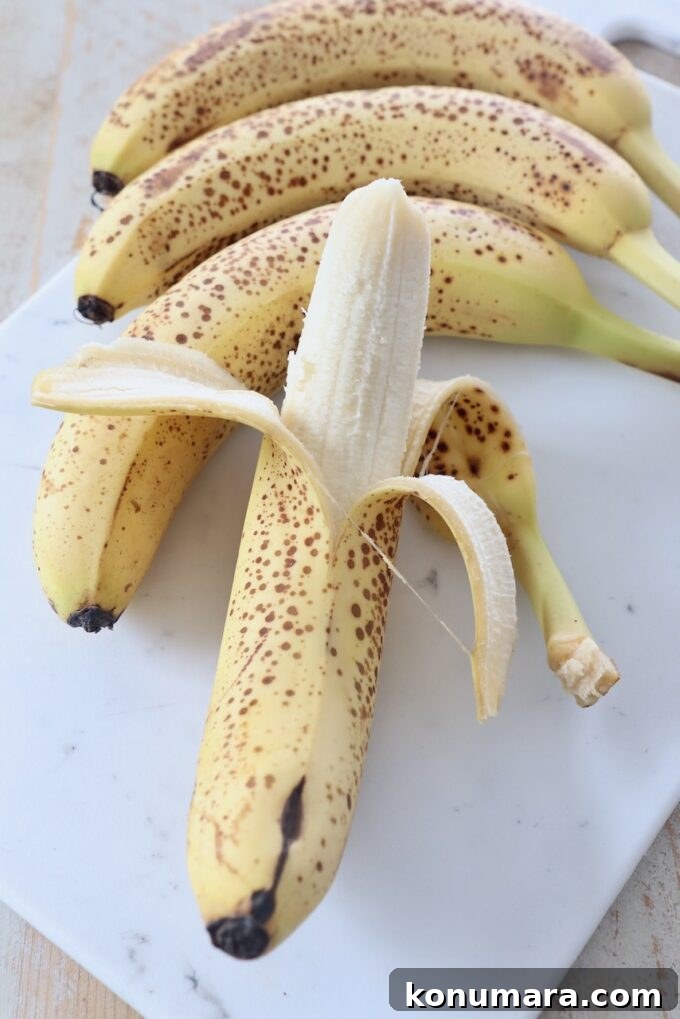 whole bananas on cutting board with one partially peeled