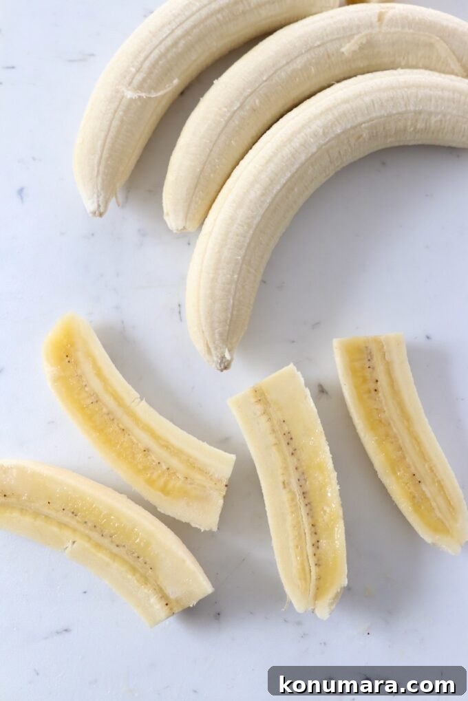 peeled bananas on cutting board, one sliced into quarters