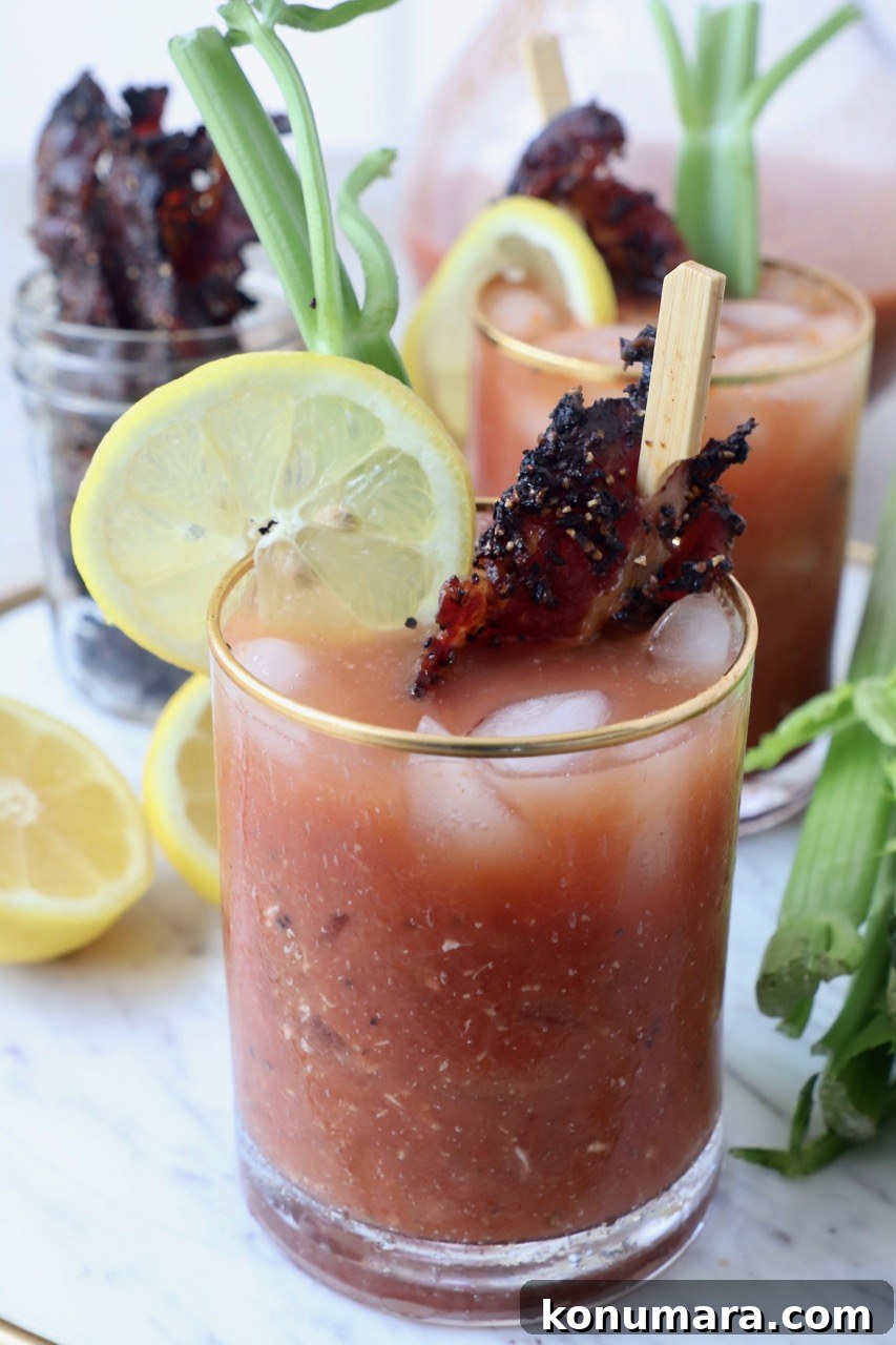bloody mary in glass with candied bacon and lime wedge
