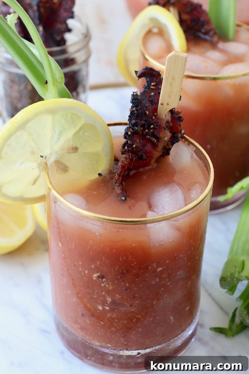 bloody mary in glass with cooked bacon and slice of lemon