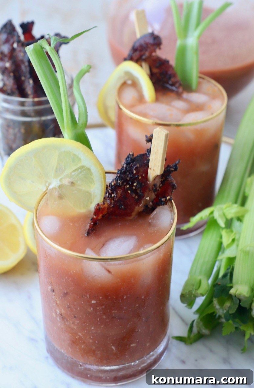 bloody mary in glasses with celery sticks, lemon slices and bacon